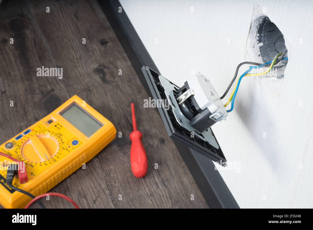 Electrician a wall socket with electronic multimeter Stock Photo Alamy