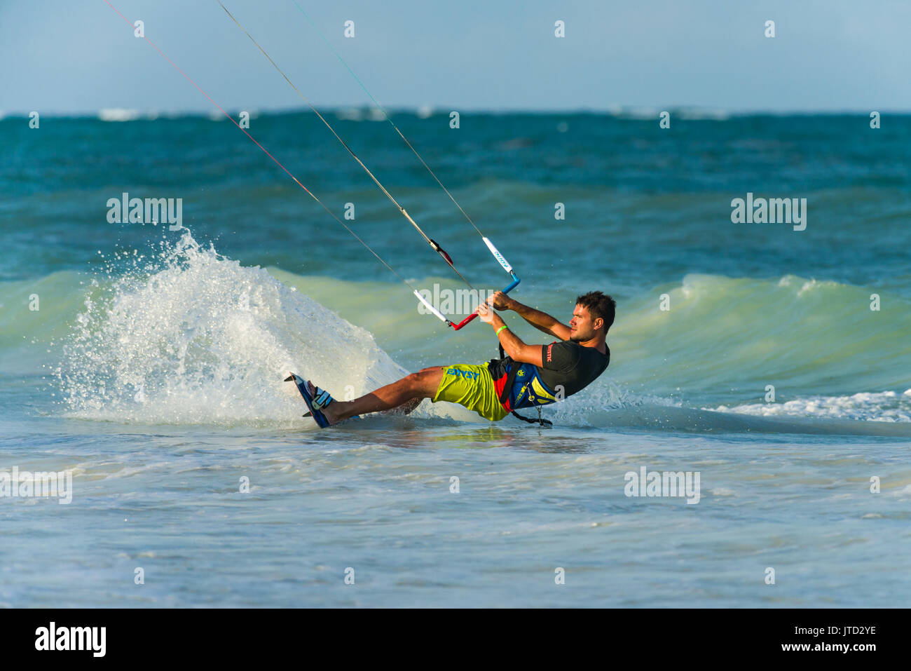 Kite surfer surfing close to shore on board in late afternoon light, Diani, Kenya Stock Photo