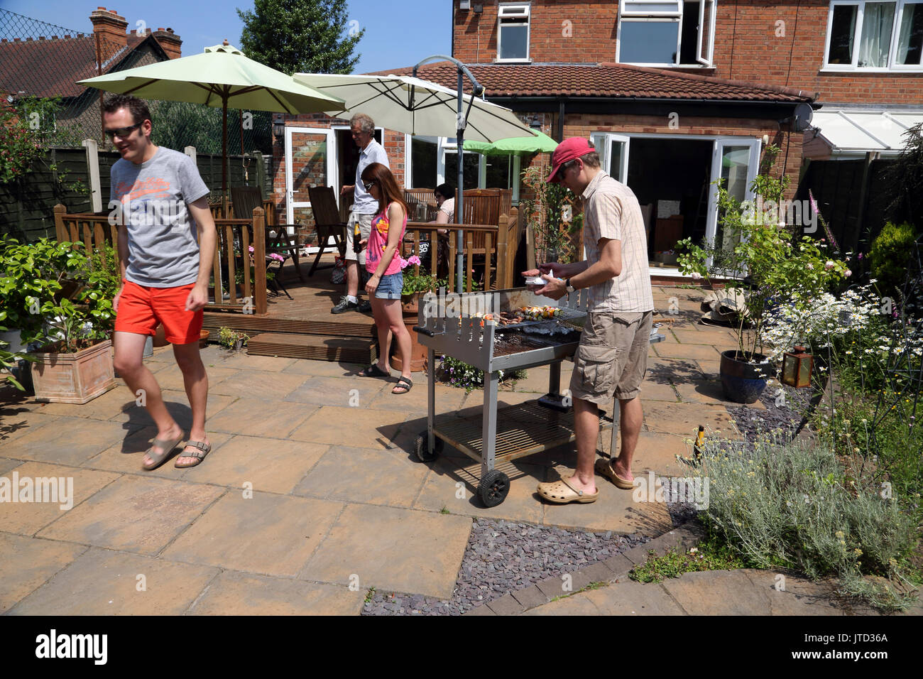 Family Having A Barbeque In Garden During The Summer Birmingham West Midlands England Stock Photo