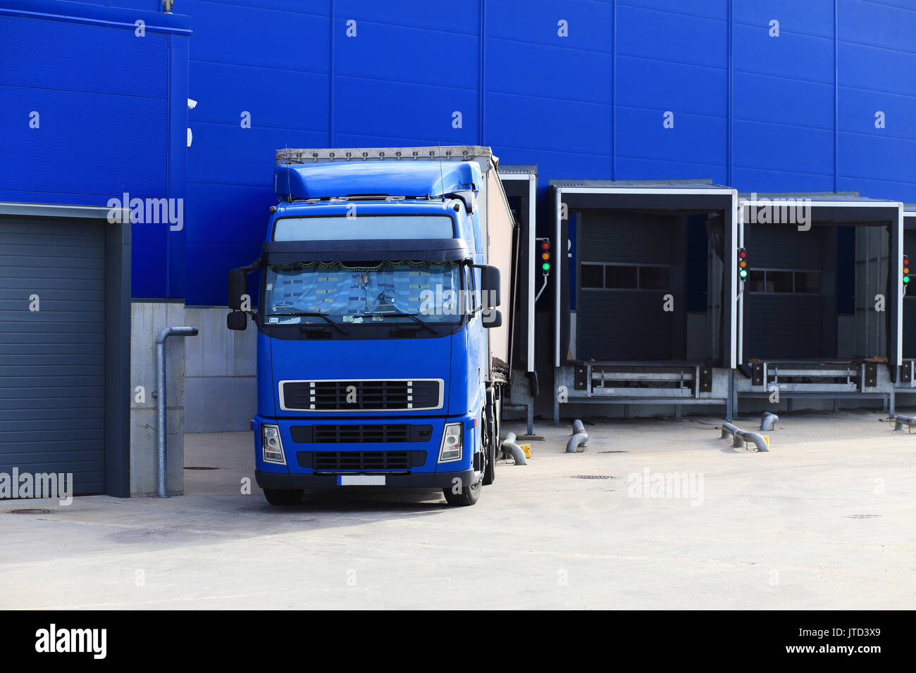 Blue truck at loading docks. Truck unloading cargo. Cargo transportation background. Stock Photo