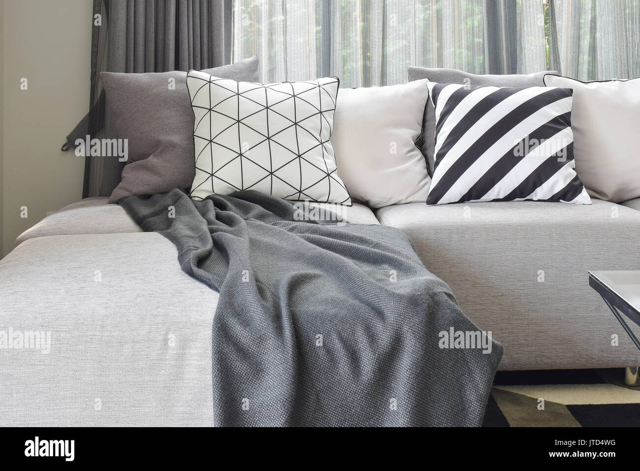 Light gray L shape sofa with varies pattern and white pillows in modern living corner Stock