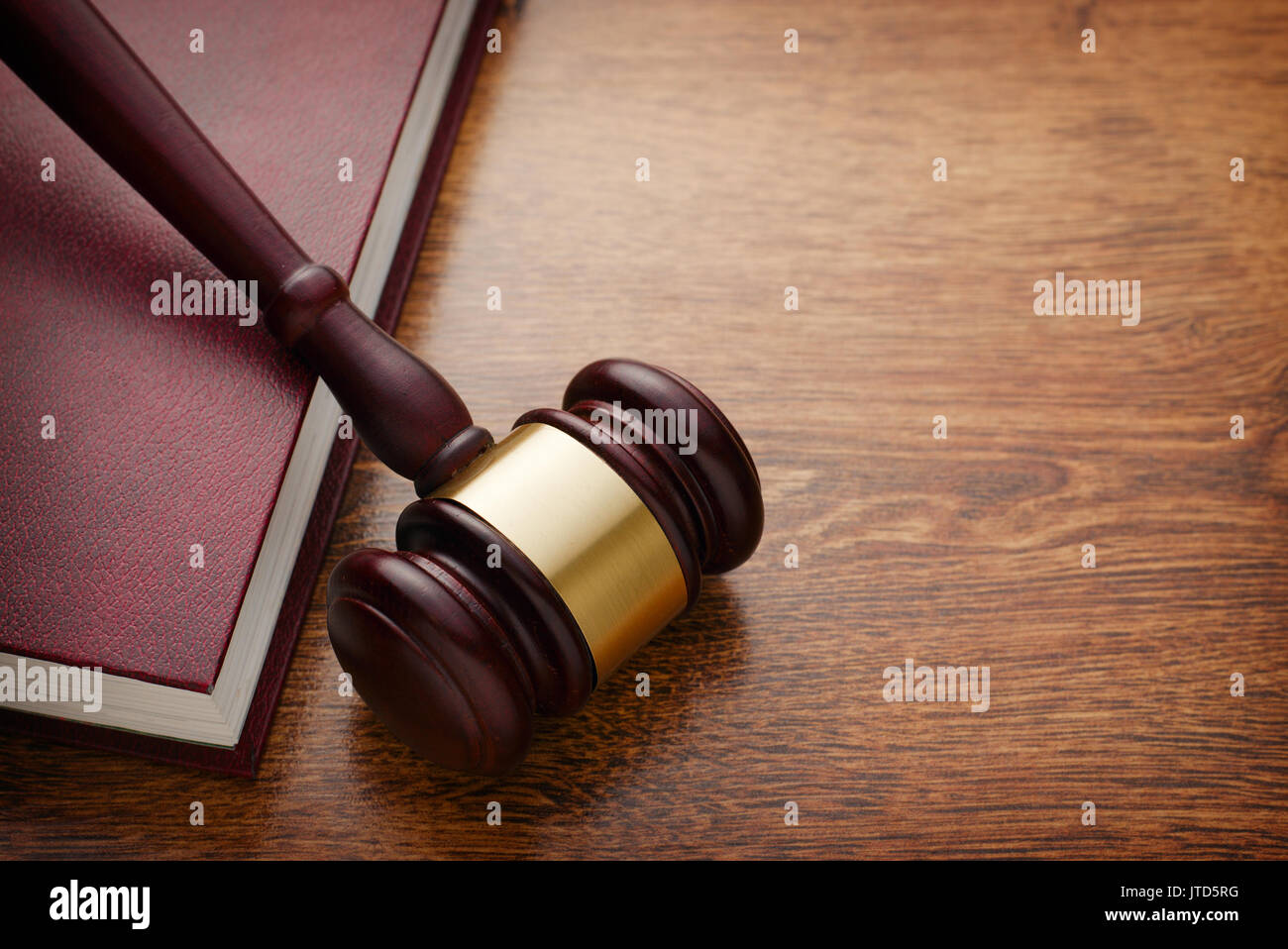 Close up Brown Wooden Gavel and Maroon Book on Top of Wooden Table, Emphasizing Legal or Law Concept Stock Photo