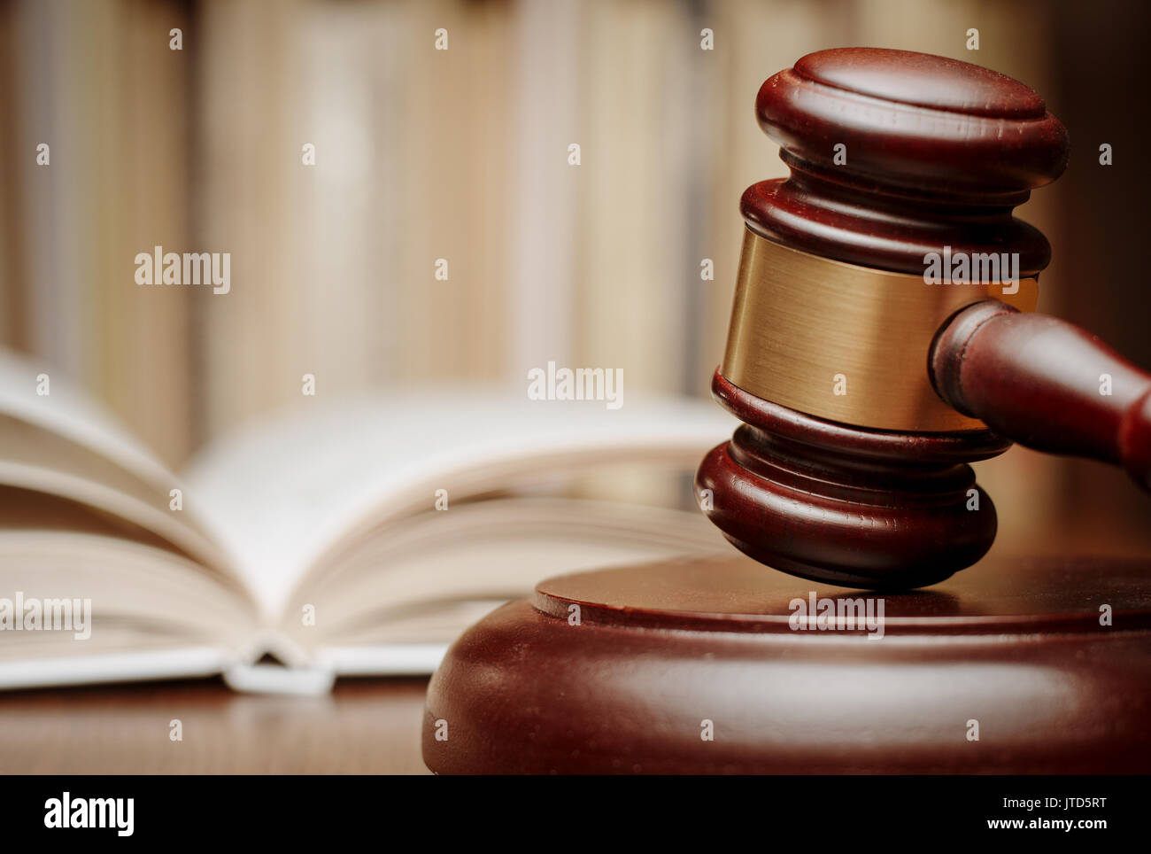 Wooden gavel resting on its end on a wooden table in front of an open law book conceptual of a judge, courtroom and judgements Stock Photo
