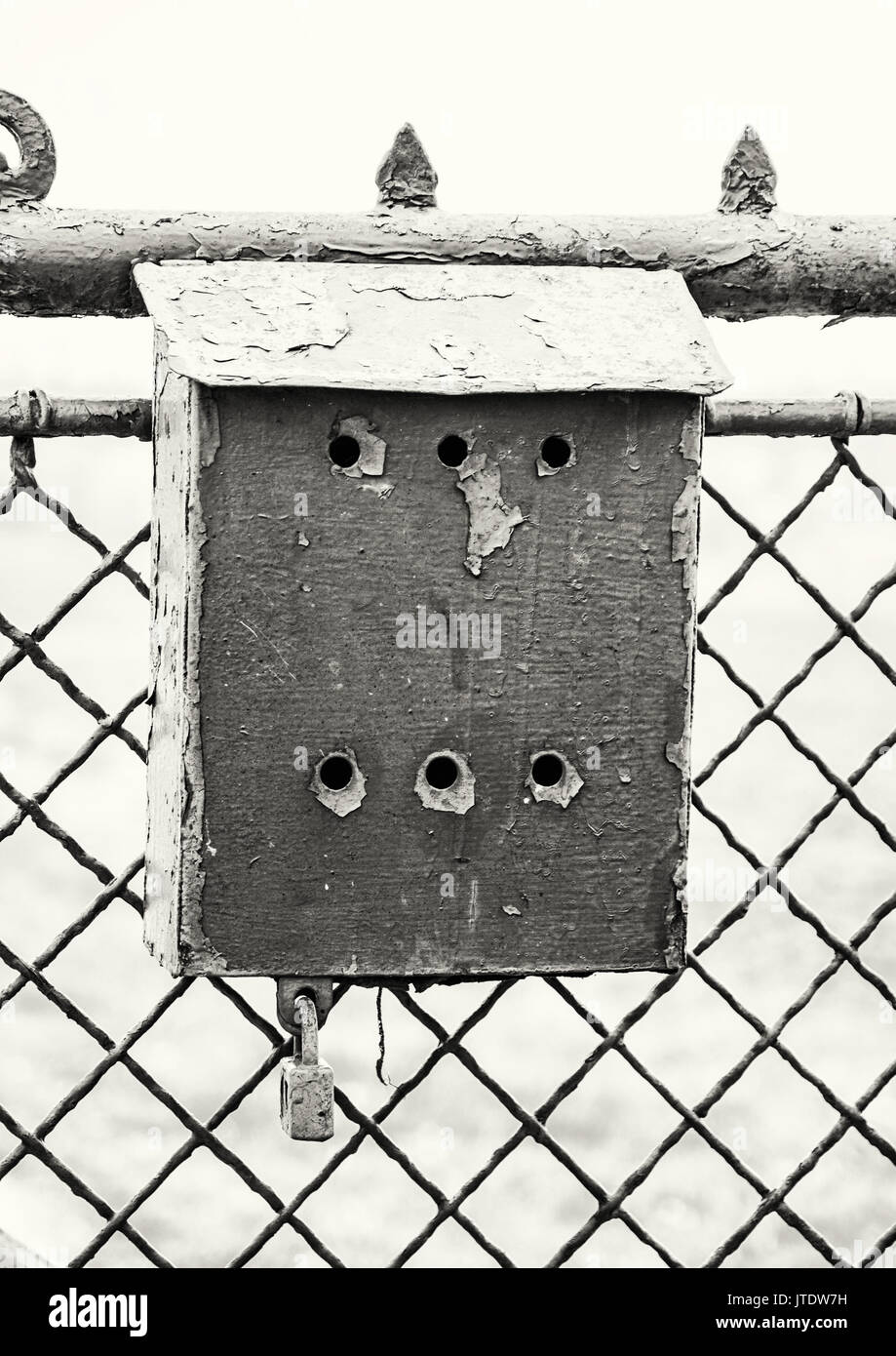 Old metallic mailbox on the fence. Mail delivery. Black and white photo. Stock Photo