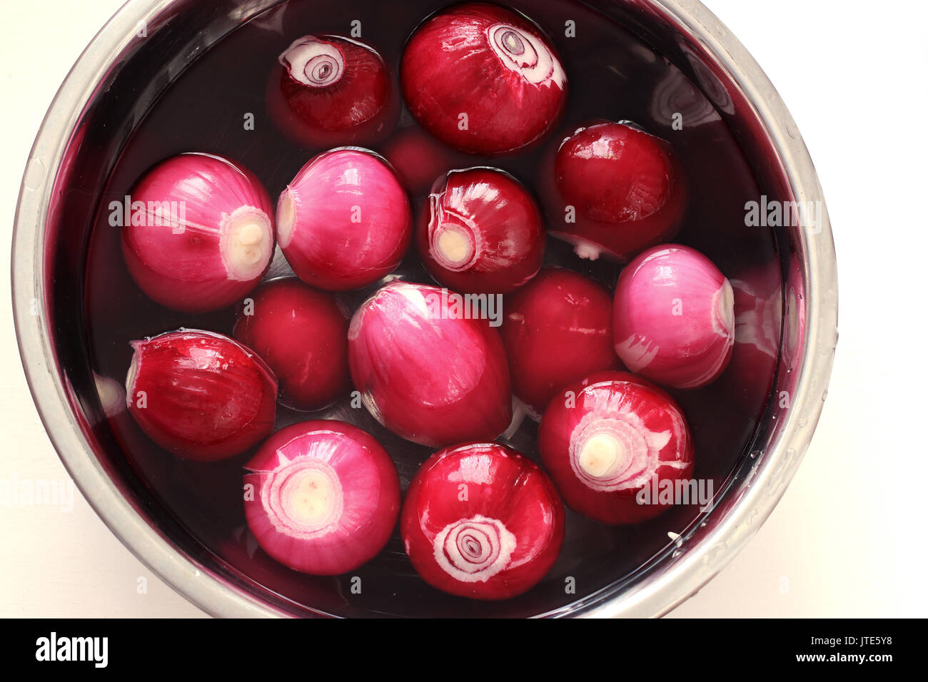 Allium cepa or known as Red onions with skin off  soaking in the water Stock Photo