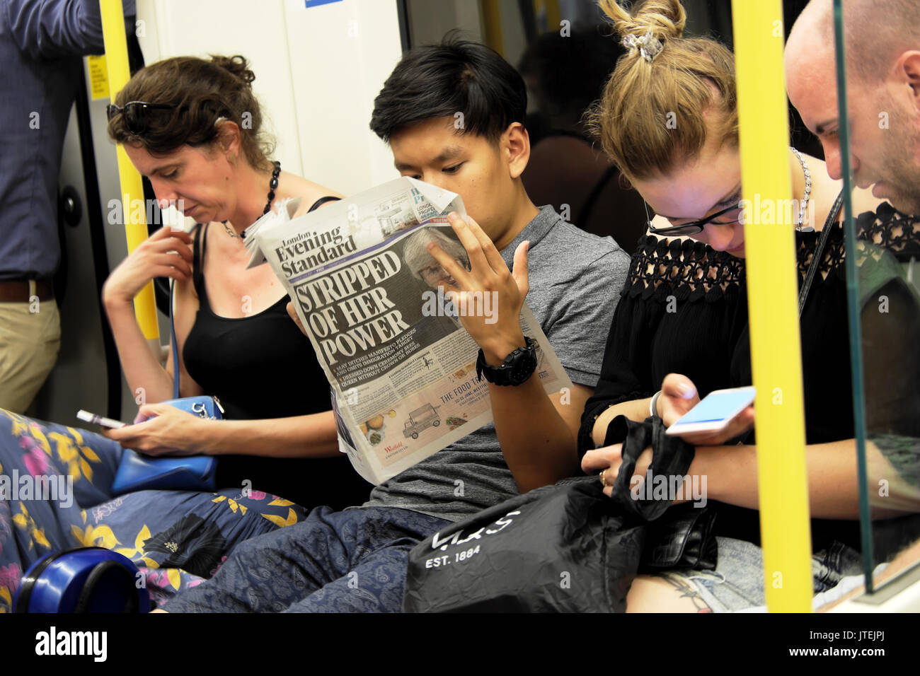 Man reading Evening Standard on train PM Theresa May newspaper headline  'Stripped of Her Power' on London tube underground carriage UK KATHY DEWITT Stock Photo
