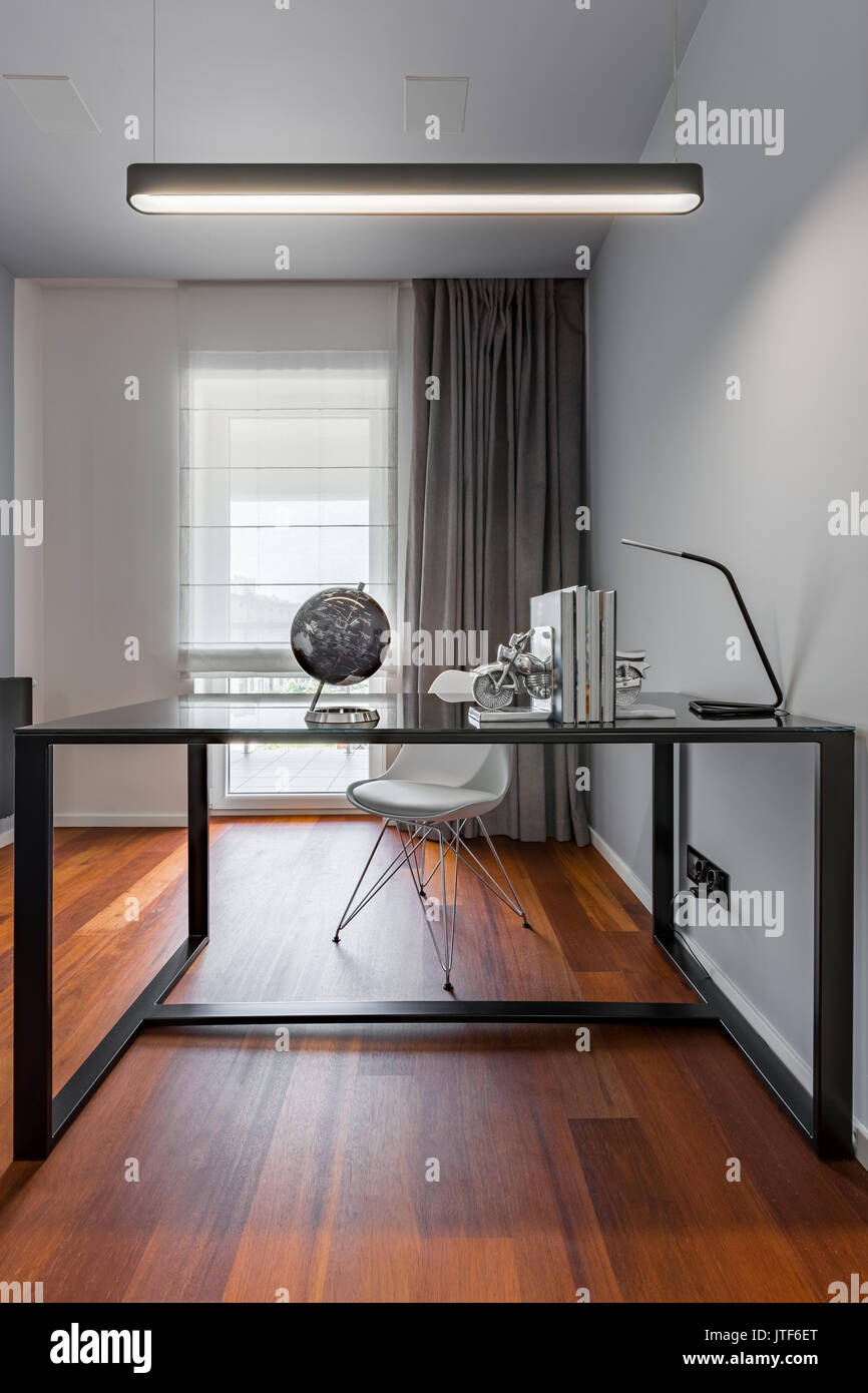 Home office with black table, simple lamp and white chair Stock Photo