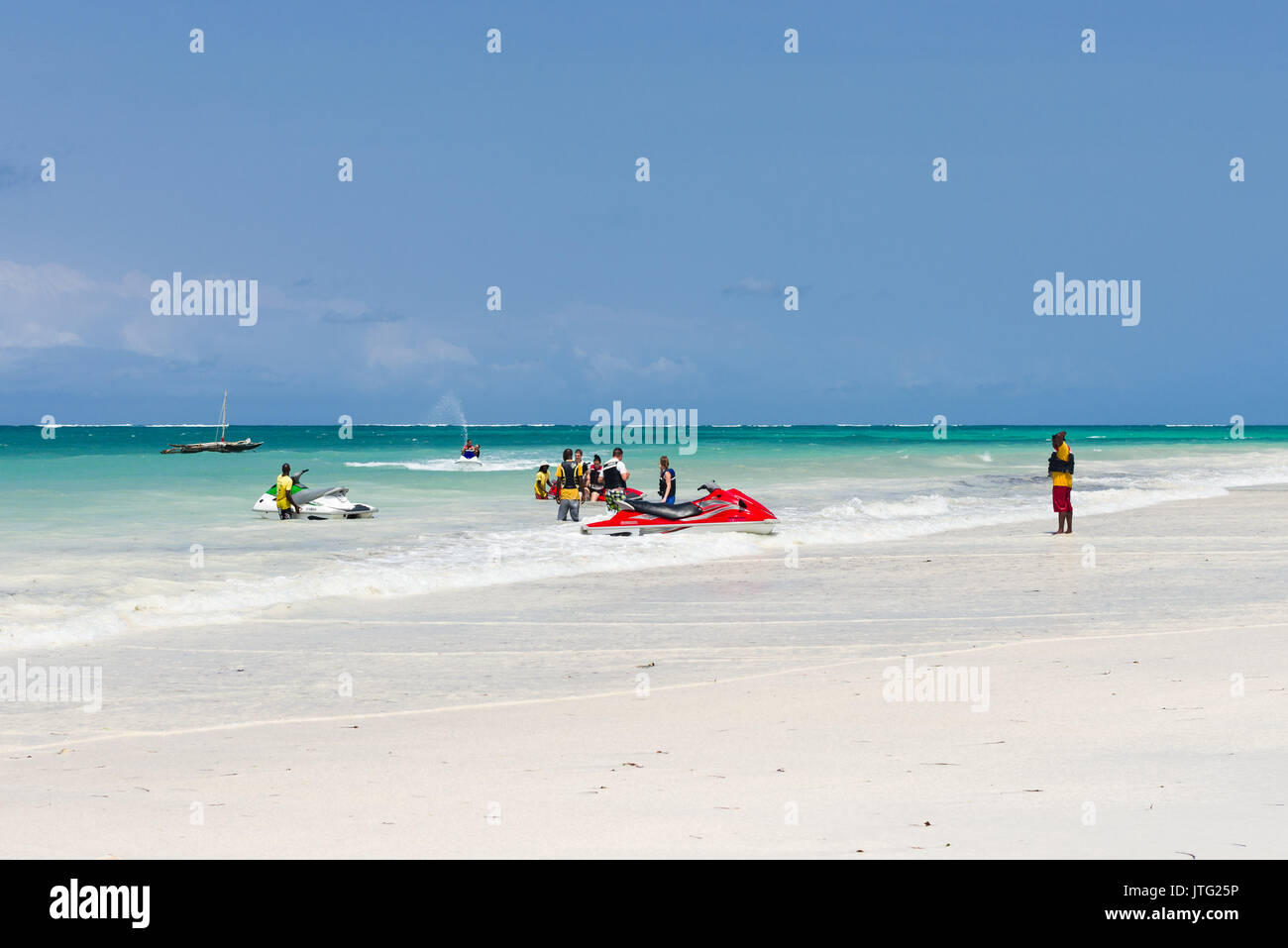 People on beach and in water unloading jet skis in to the ocean, Diani, Kenya Stock Photo