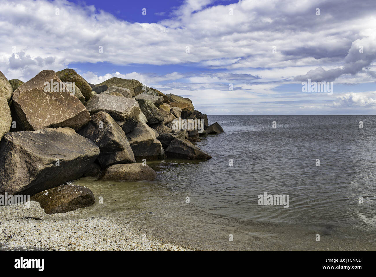 Large rocks on the beach with a cloudy blue sky background Stock Photo ...
