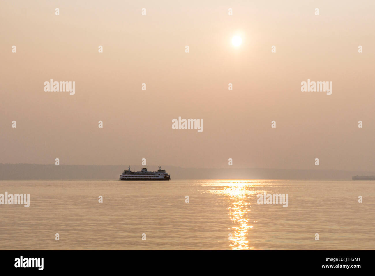 Puget Sound, Edmonds Washington, USA. 08th Aug, 2017. smoke drifting south from Canadian forest fires in British Columbia gives Edmonds, Washington, USA a beautiful hazy sunset over Puget Sound, obscuring Olympic Peninsula, as ferry glides into port on August 8, 2017 Credit: Dorothy Alexander/Alamy Live News Stock Photo