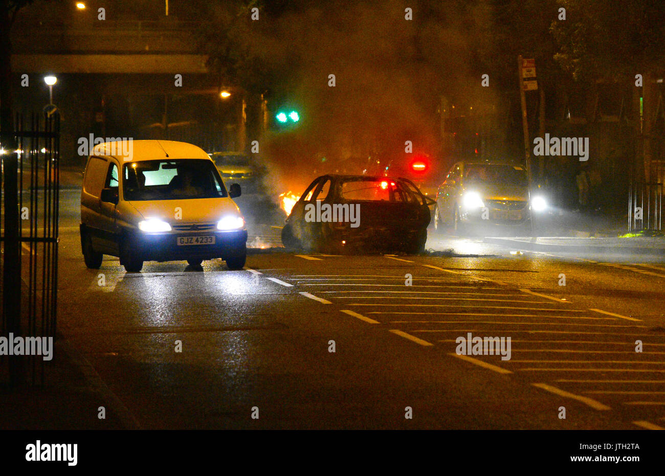 Belfast, Northern Ireland. 09th Aug, 2017. Traffic makes their way past a burning car in the middle of the road in the New Lodge area of Belfast on the evening when Bonfires are light as part of the Anti-Internment demonstrations. Belfast: UK: 09 AUG Credit: Mark Winter/Alamy Live News Stock Photo