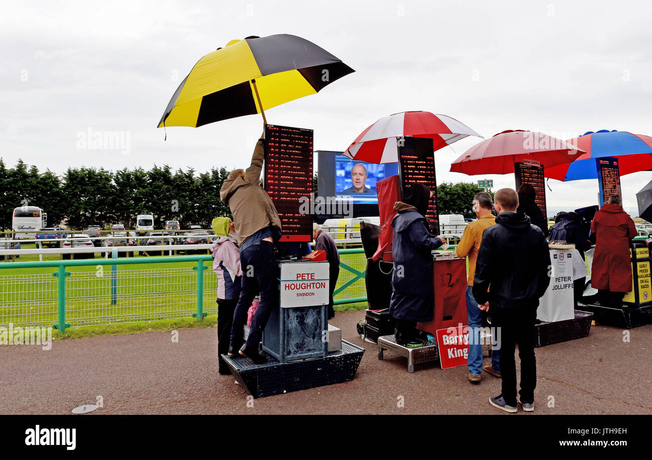 Brighton, UK. 9th Aug, 2017. A bookmaker has trouble with his giant umbrella at the Marstons Race Day in the Maronthonbet Festival of Racing at Brighton Racecourse Credit: Simon Dack/Alamy Live News Stock Photo