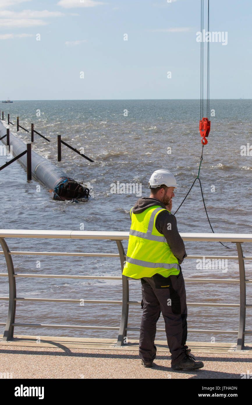 A new flood water outfall pipe has been transported by ship from Norway to the coast of Ireland and is now installed at Anchorsholme Beach, Blackpool, Lancashire. August 2017. This new extended submerged outfall pipe will discharge the excess screened stormwater out to sea and is part of improvements to the Fylde coast water management system. Filled with air to keep it afloat, the 20,000-tonne pipe left Ireland on Saturday afternoon and was pulled across the Irish Sea with an escort of 4 ships. Stock Photo