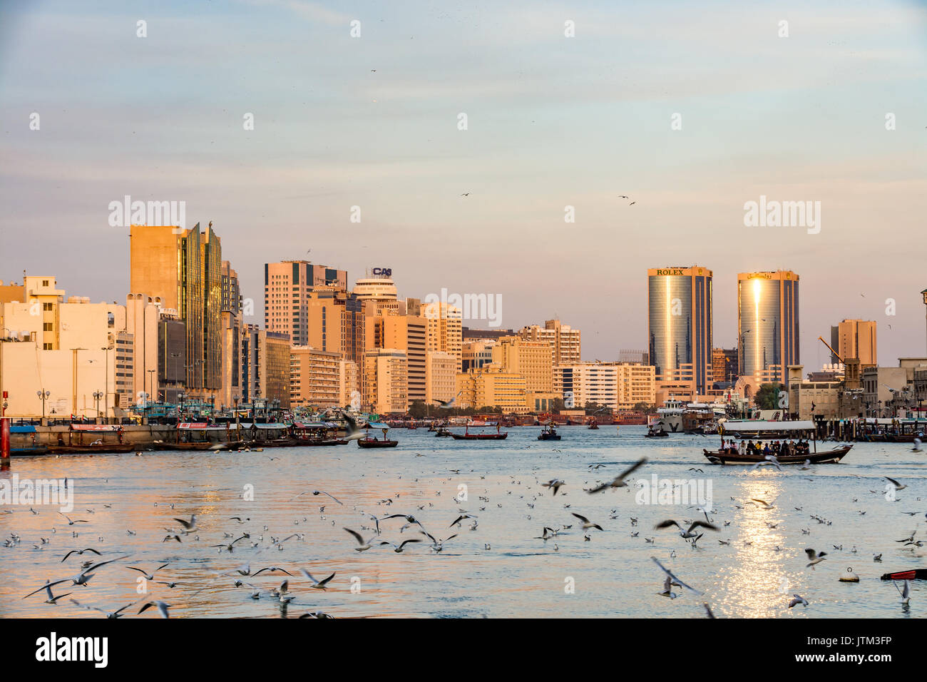 View of Dubai creek with lots of seagulls and abra boats at sunset, United Arab Emirates, UAE Stock Photo