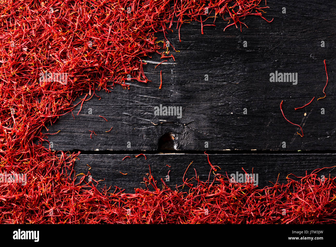 saffron crocus threads on black wooden background, full frame, view from above Stock Photo