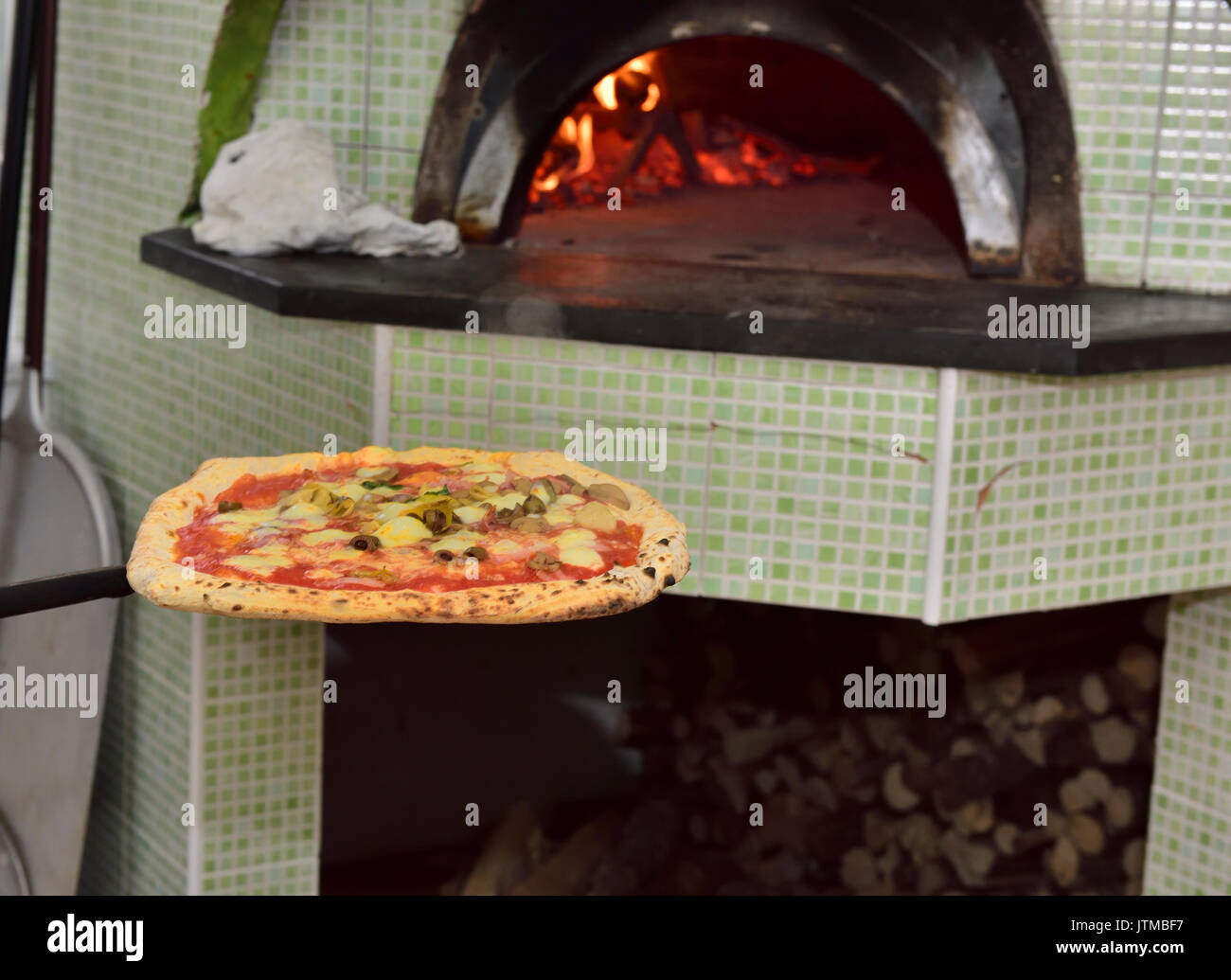 Pizza as it comes out of traditional wood burning pizza oven on paddle, Naples, Italy Stock Photo