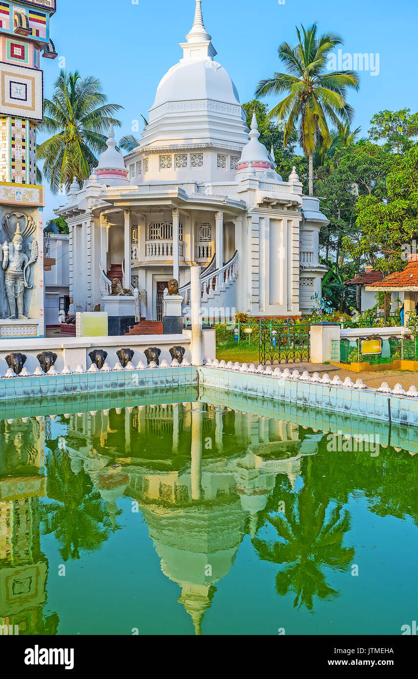 The white Stupa is reflected in green waters of the pool of Angurukaramulla Temple (Bodhirajaramaya), Negombo, Sri Lanka. Stock Photo