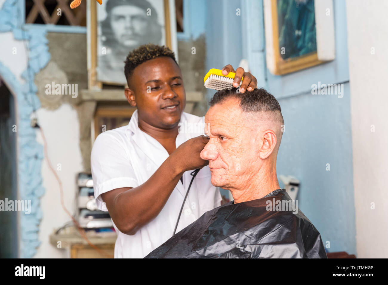 Barber cutting a Cuban man's hair in a and hairdressing