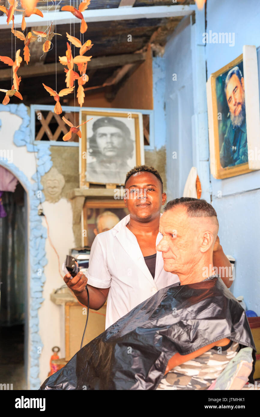 Barber cutting a Cuban man's hair in a typical and