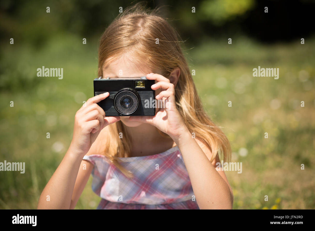 Little girl taking pictures with vintage camera. Stock Photo
