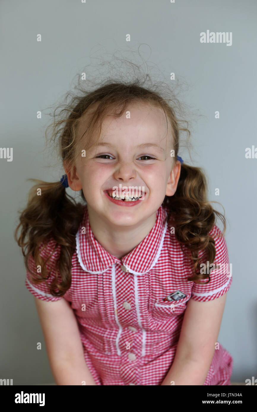 Isabelle, 5, pictured in her school uniform after her first tooth has fallen out at her home in Sussex, UK. Stock Photo