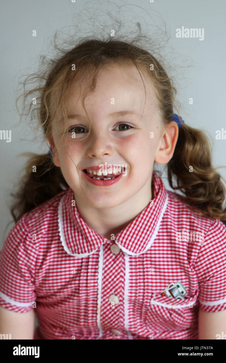 Isabelle, 5, pictured in her school uniform after her first tooth has fallen out at her home in Sussex, UK. Stock Photo