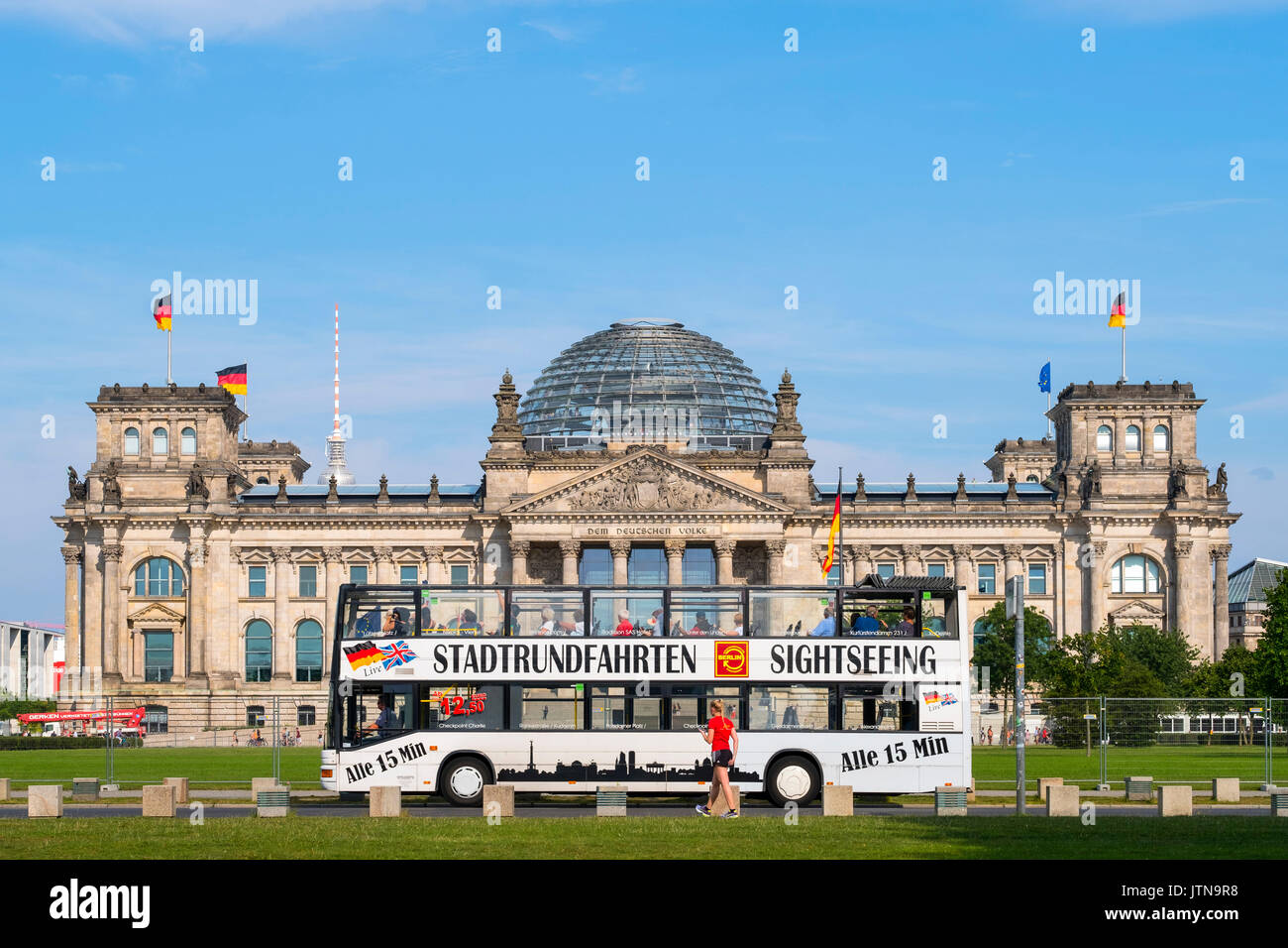 Tourist sightseeing city bus tour passes the German Reichstag parliament building in Berlin Germany Stock Photo