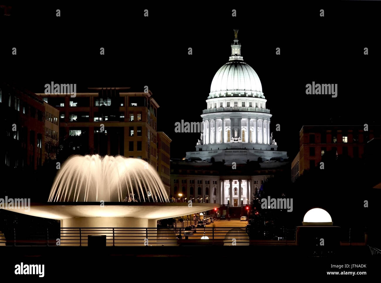 National Historic Landmark. Madison, Wisconsin, USA. Night scene with official buildings and illuminated fountain on the foreground. View from Monona  Stock Photo