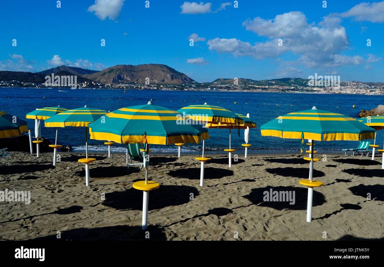 Beautiful beach  of Baia, Naples in Italy.Before the day ends in the resort umbrellas standing in the beach adding beautiful colours to the landscape Stock Photo