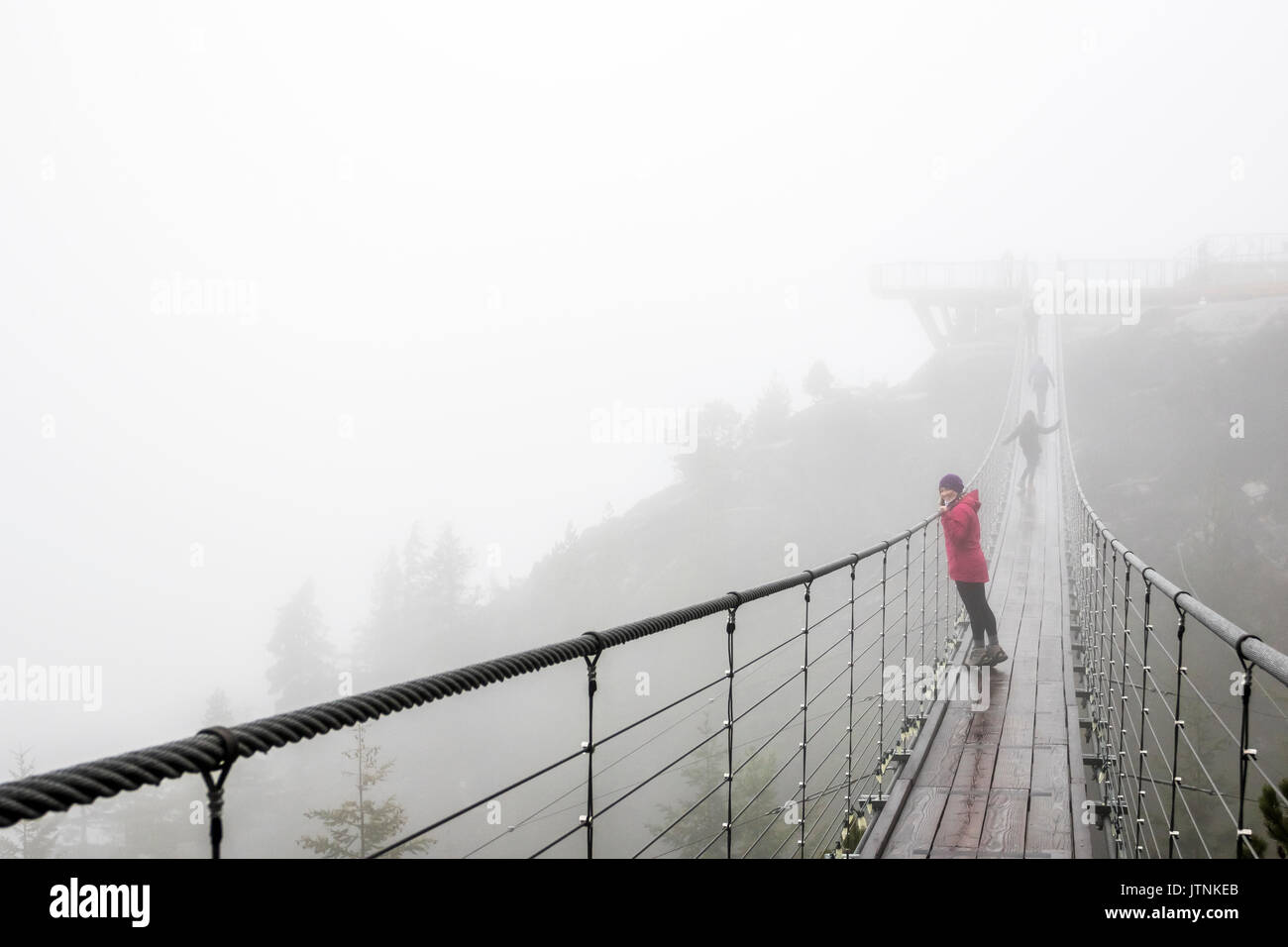 A women looks over a suspension bridge on a rainy fall day in Squamish, British Columbia. Stock Photo