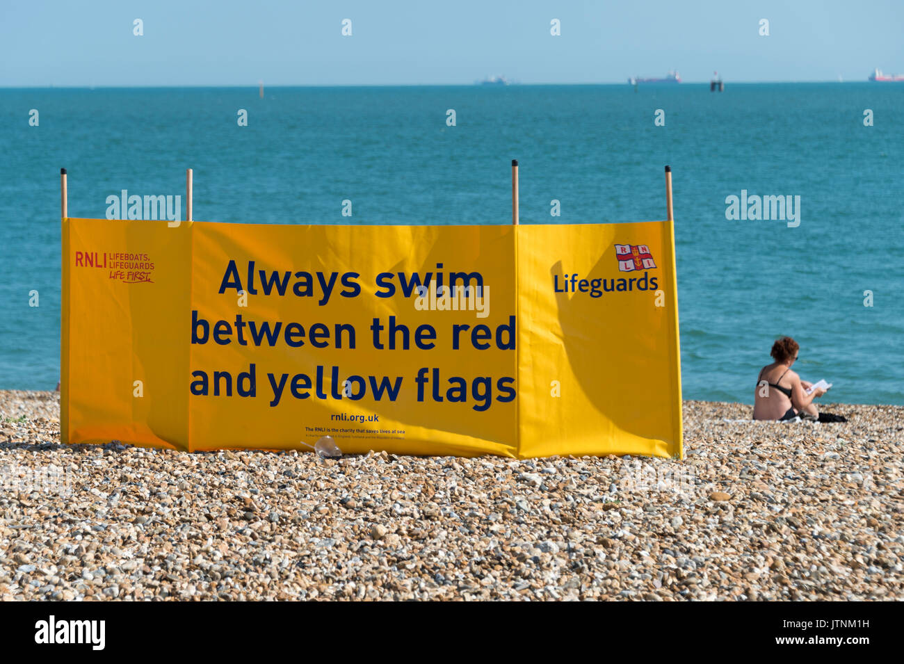 RNLI lifeguard windbreak sign on Southsea beach in Hampshire. Swim betweeneo red & yellow flags Stock Photo
