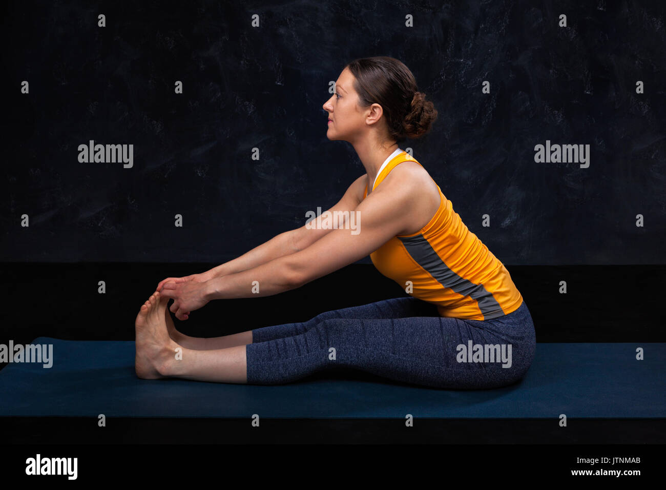 Woman doing Hatha yoga Ashtanga Vinyasa yoga asana Paschimottana Stock Photo