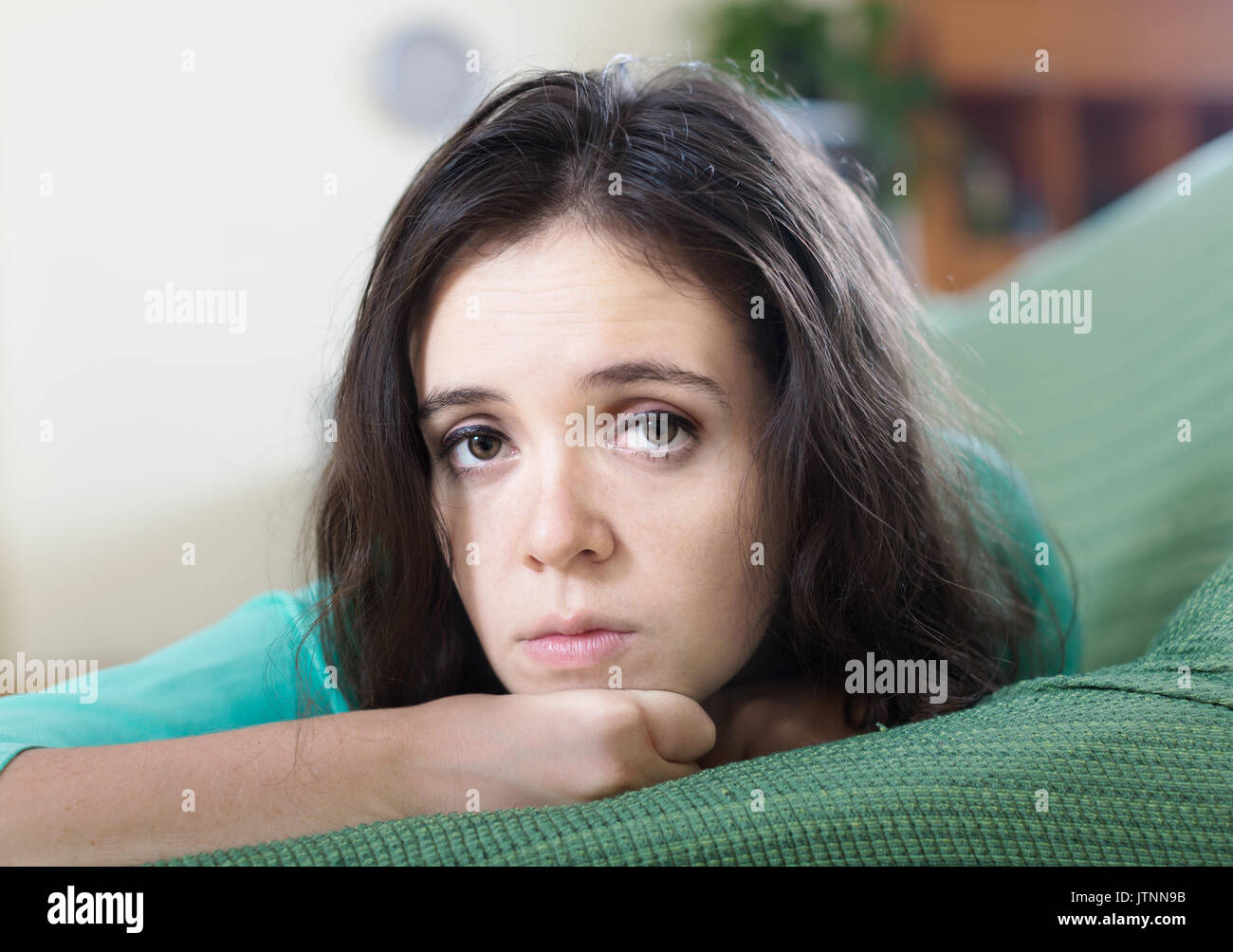 sad brunette woman lying on sofa at home Stock Photo - Alamy