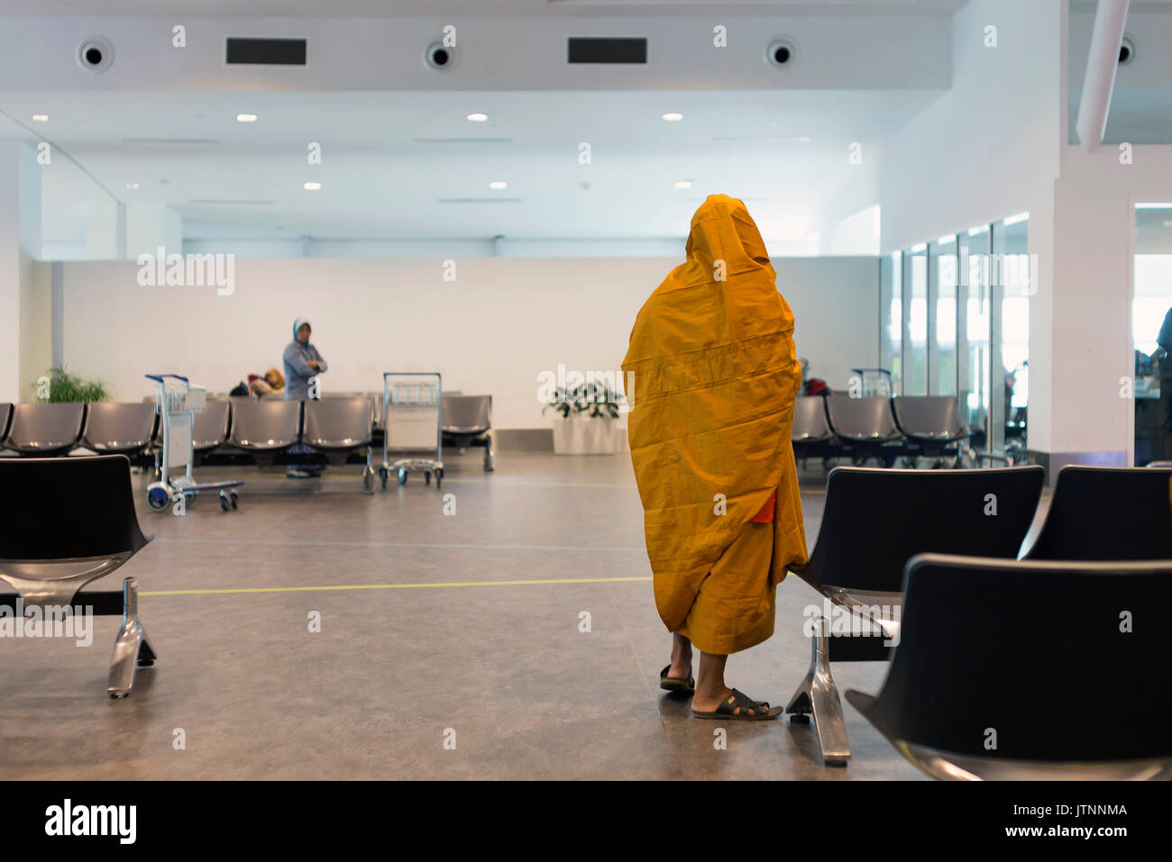 Buddhist monk waiting at airport departure lounge,Kuala Lumpur,Malaysia Stock Photo