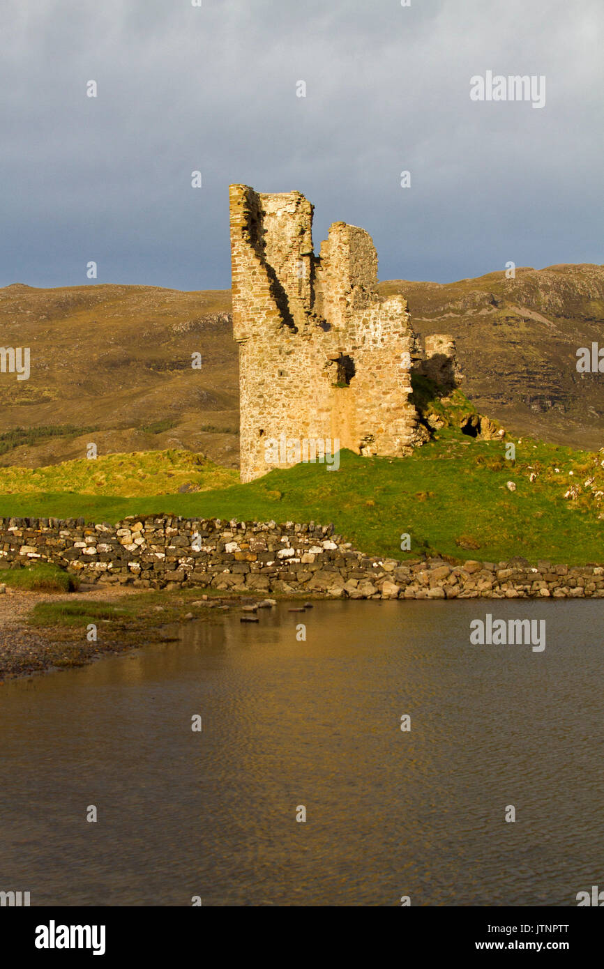 Crumbling ruins of Ardvreck castle beside calm dark water of Loch Assynt in Scotland Stock Photo