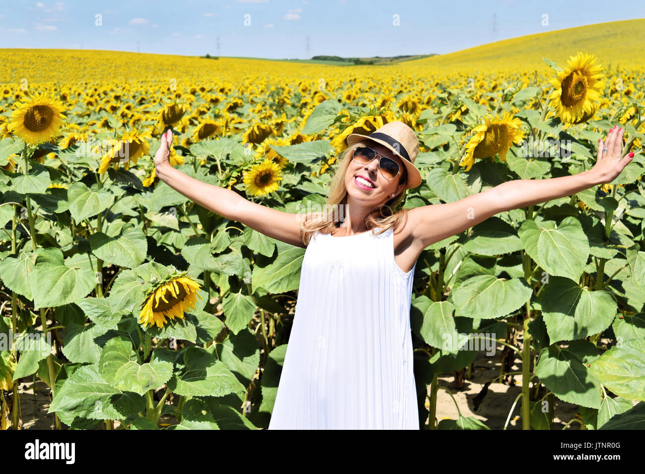 Cheerful girl in a sunflower farm enjoying the sun Stock Photo - Alamy