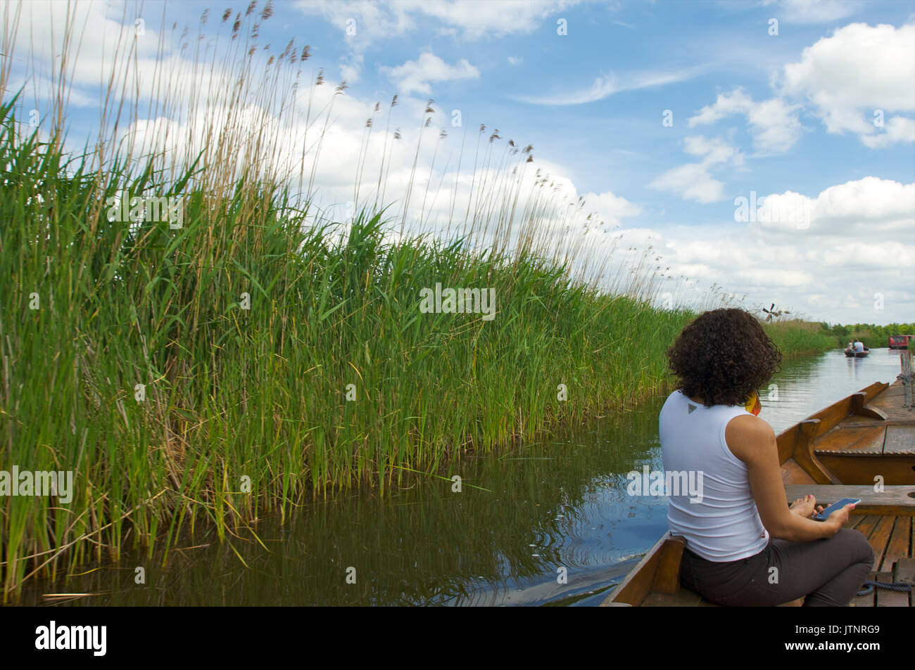 Wioman in a wooden boat sailing through a canal near Giethoorn, the Netherlands Stock Photo