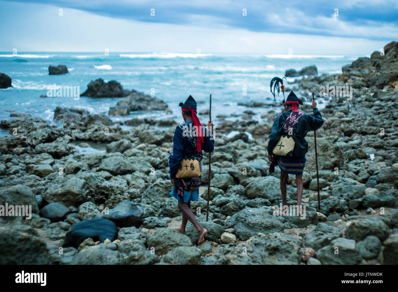 Two shamans with spears standing by ocean, Sumba Island, Indonesia Stock Photo