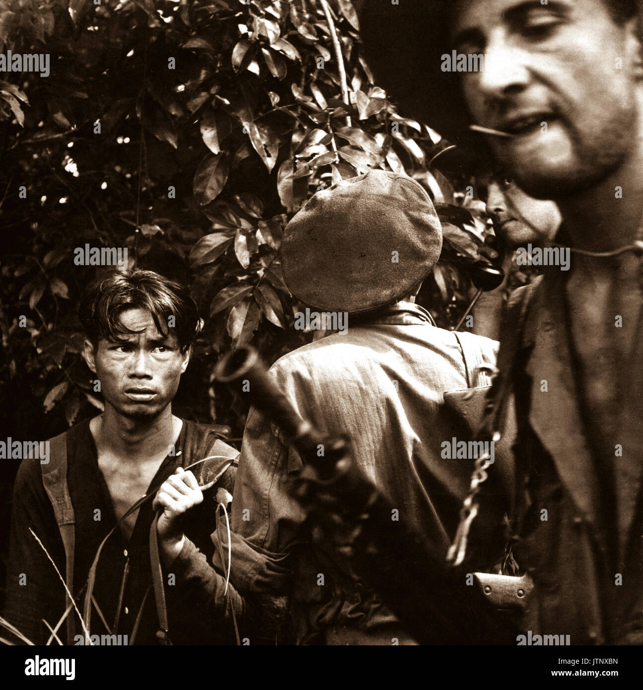 The French Foreign Legion is playing the major combat role in the war against the Vietminh.  Here a red-suspect has been found hiding in the jungle and is now being questioned by the advance patrol, who caught him.  Ca.  1954.  Pix.  (USIA) EXACT DATE SHOT UNKNOWN NARA FILE #:  306-PS-55-10516 WAR & CONFLICT BOOK #:  383 Stock Photo