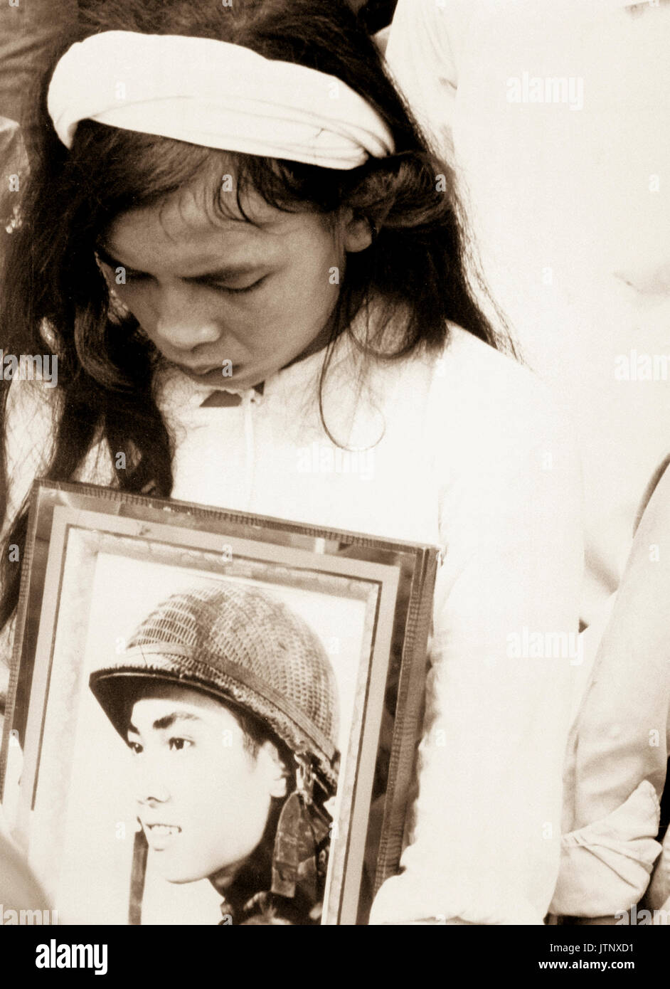 Almost 400 men, women and children massacred by the Viet Cong during 'Tet 1968' were mourned at a common-grave burial on October 14.  This young widow, carrying a photograph of her missing husband, mourns at the mass funeral service.  Hue, 1968.  (USIA) NARA FILE #:  306-MVP-4-8 WAR & CONFLICT BOOK #:  427 Stock Photo