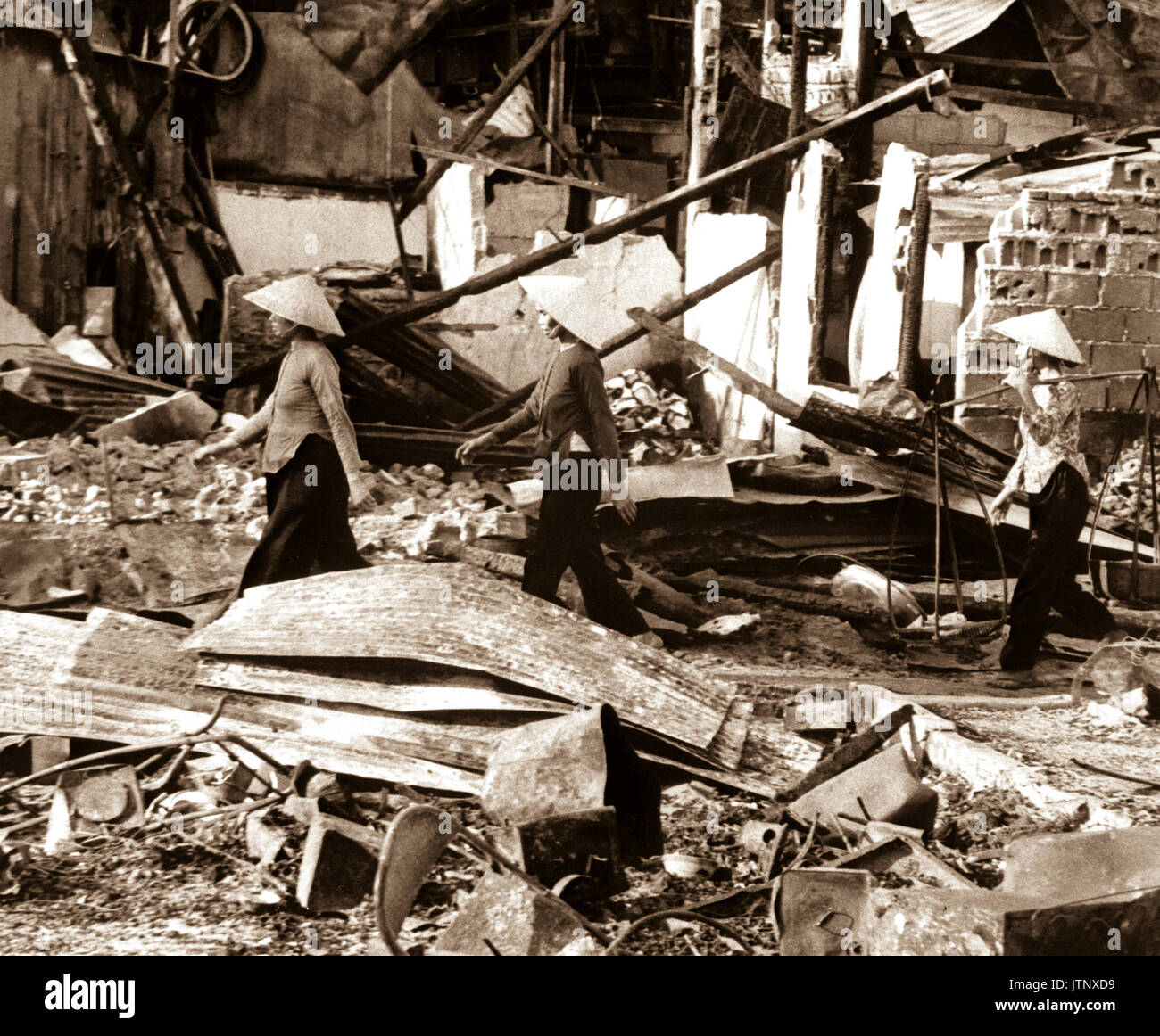 Three Vietnamese women move back into the Cholon area after VC attack that left a two-block area leveled, in hopes of salvaging meager belongings.  Saigon, January 31, 1968.  (USAIA) NARA FILE #:  306-MVP-5-4 WAR & CONFLICT BOOK #:  421 Stock Photo