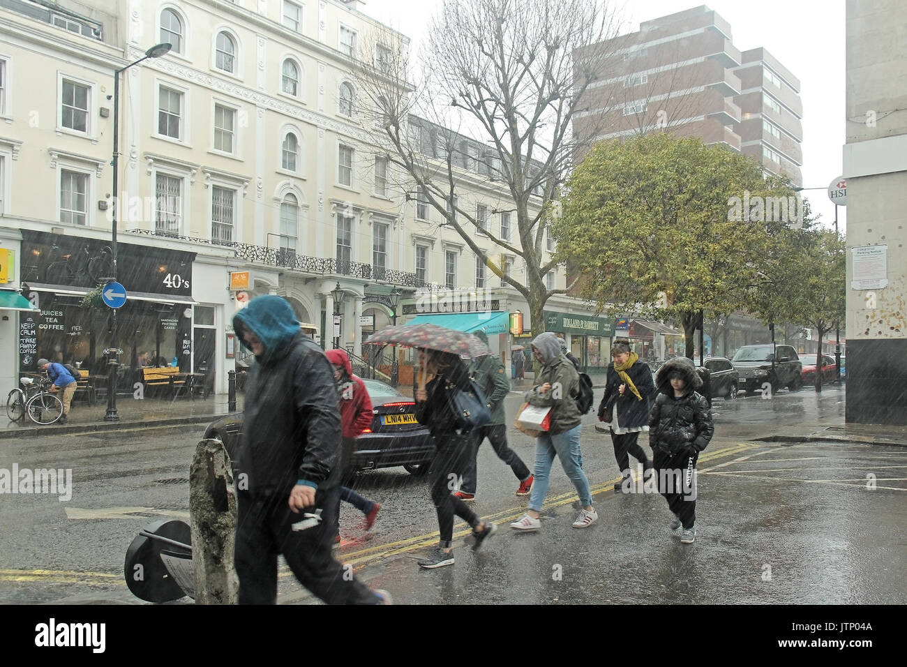Rain falling in London showing typical weather condition with people on street carrying