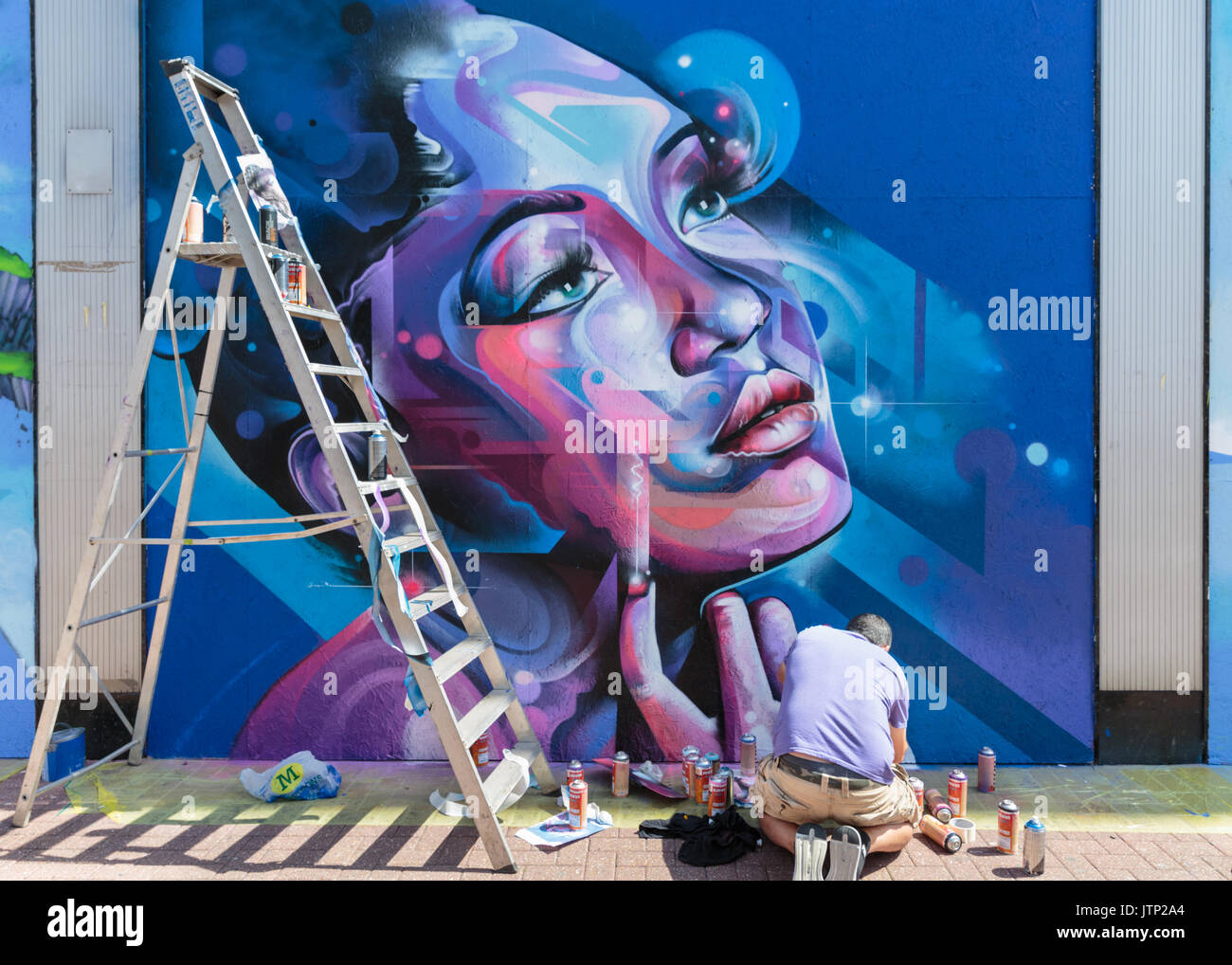 Artist Mr. Cenz spraying a commissioned street art work in Southendon