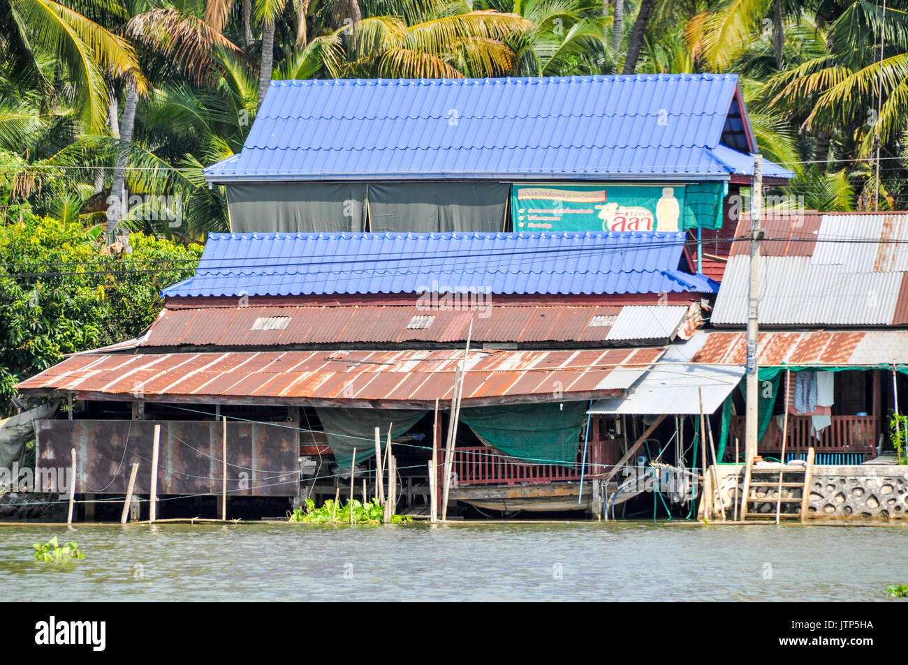 A ramshackle house on the banks of a river in Thailand. Stock Photo
