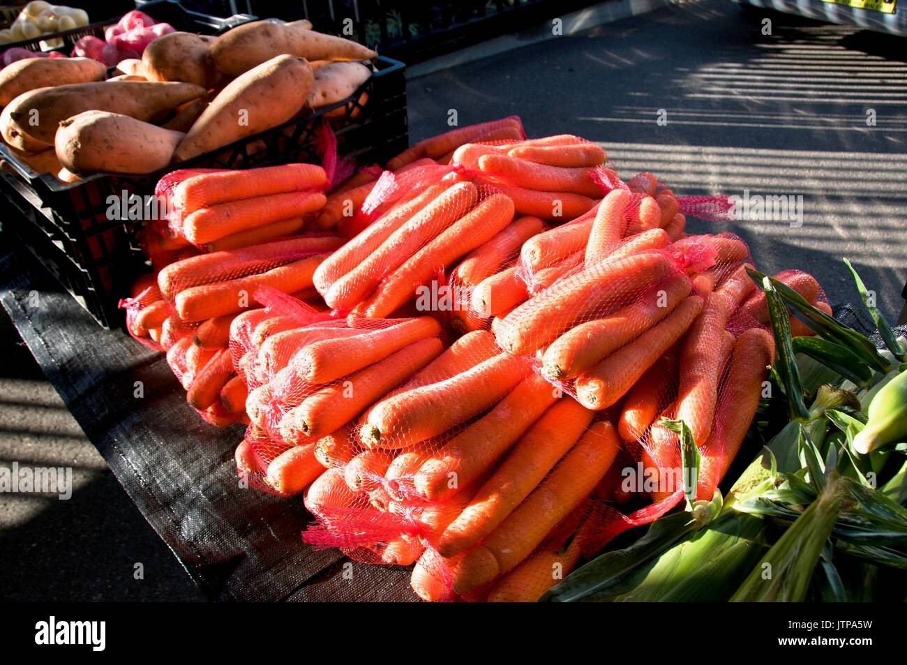 A table display of fresh nutritious vegetables at a farmer's market,  includes, Carrots - (Daucus carota subsp. sativus), and Sweet Potato - (Ipomoea  Stock Photo