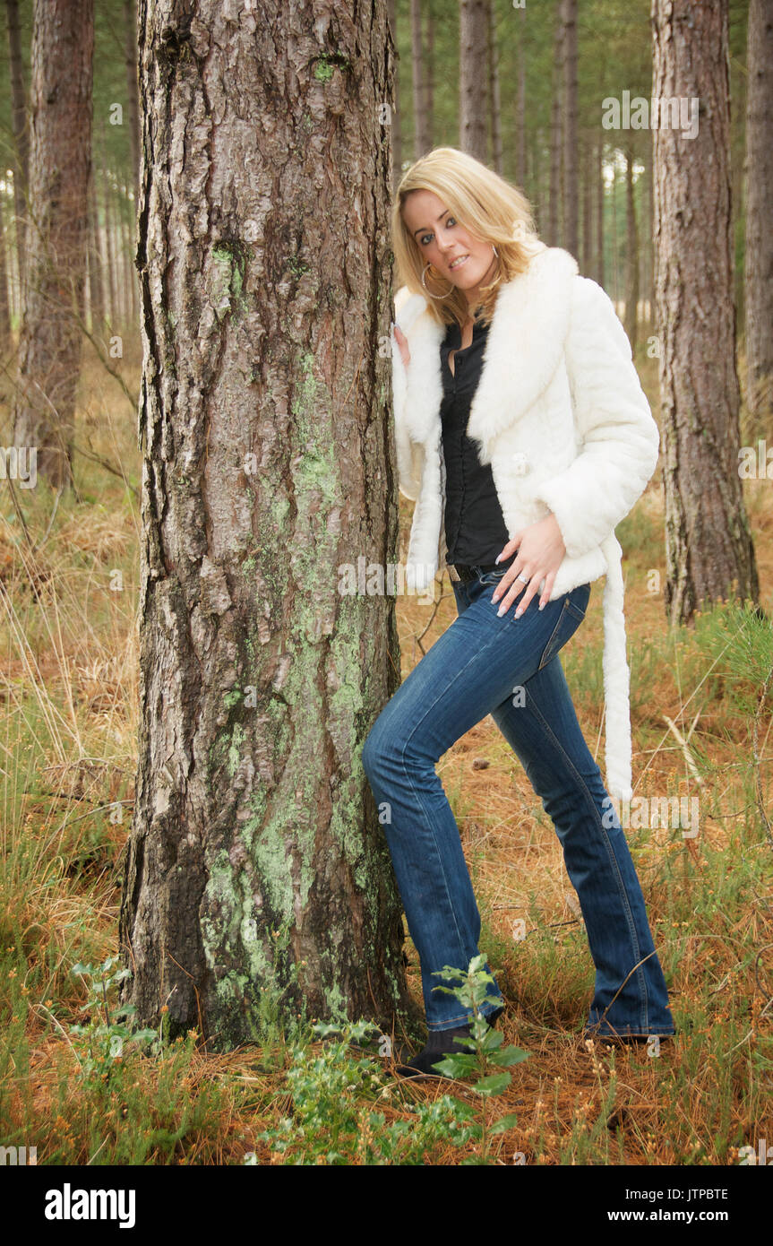 Pretty blonde girl in a forest wearing jeans and a white jacket Stock ...