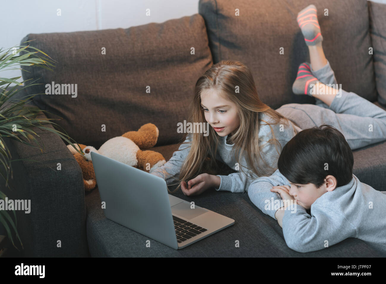 little boy and girl using laptop on sofa together Stock Photo