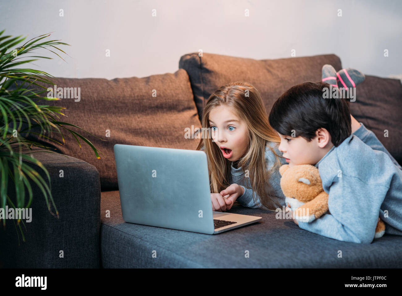 adorable shocked girl and boy using laptop at home Stock Photo