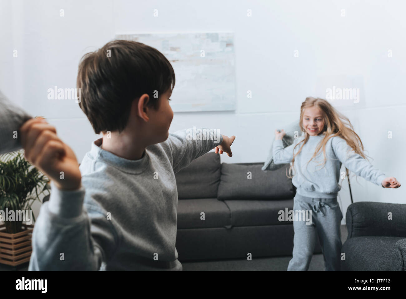 little boy and girl playing pillow fight at home Stock Photo