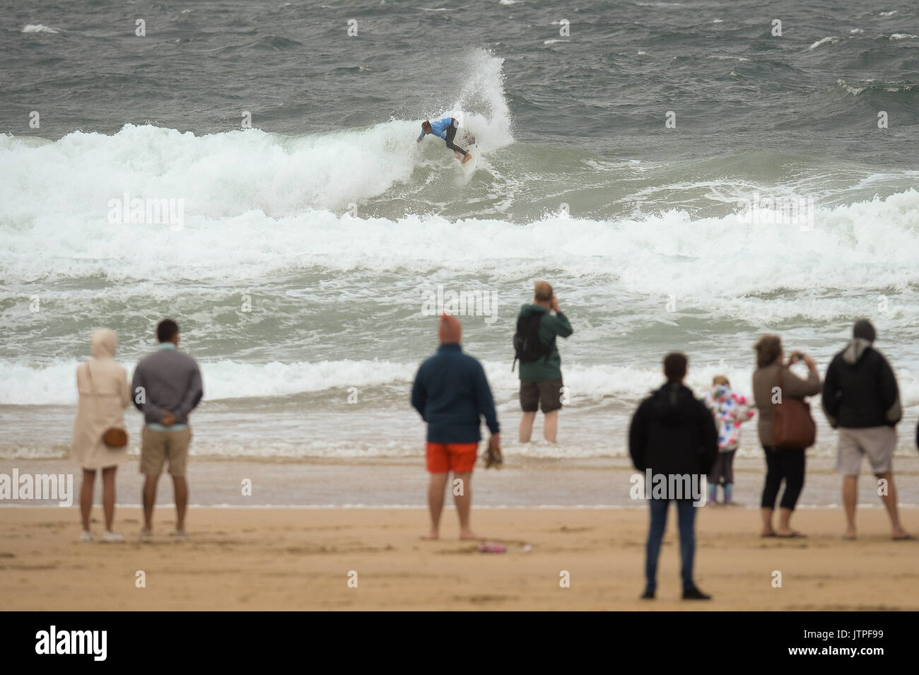 Spectators watch surfers during heats for the World Surf League Boardmasters Quicksilver Open competition at Fistral beach in Newquay, Cornwall. Stock Photo